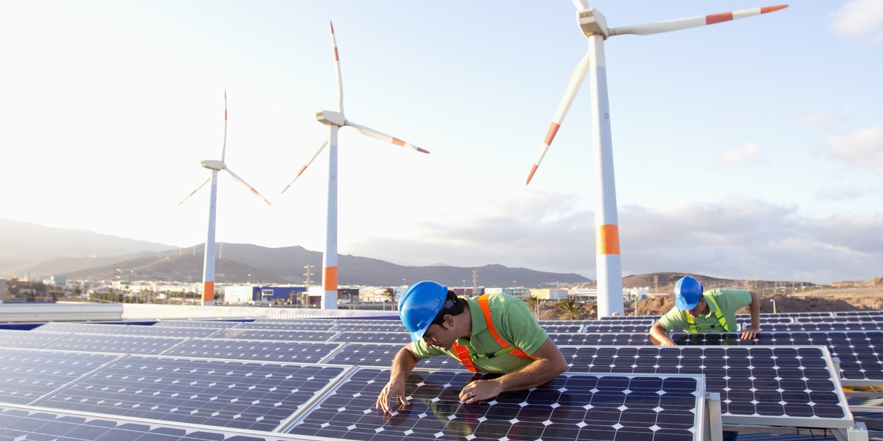 Photovoltaik-Installateure und Windräder im Hintergrund