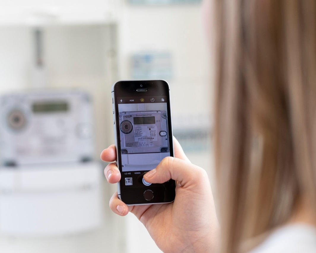 Frau erfasst ihren Zählerstand mit der Smartphone Kamera in der NetzkundenApp.